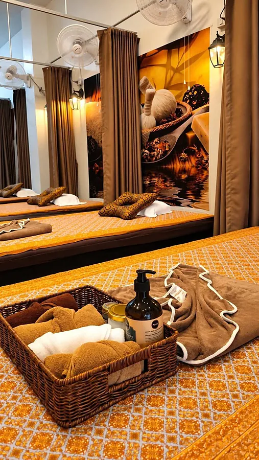 A basket of oils and fresh towels on a massage bed
